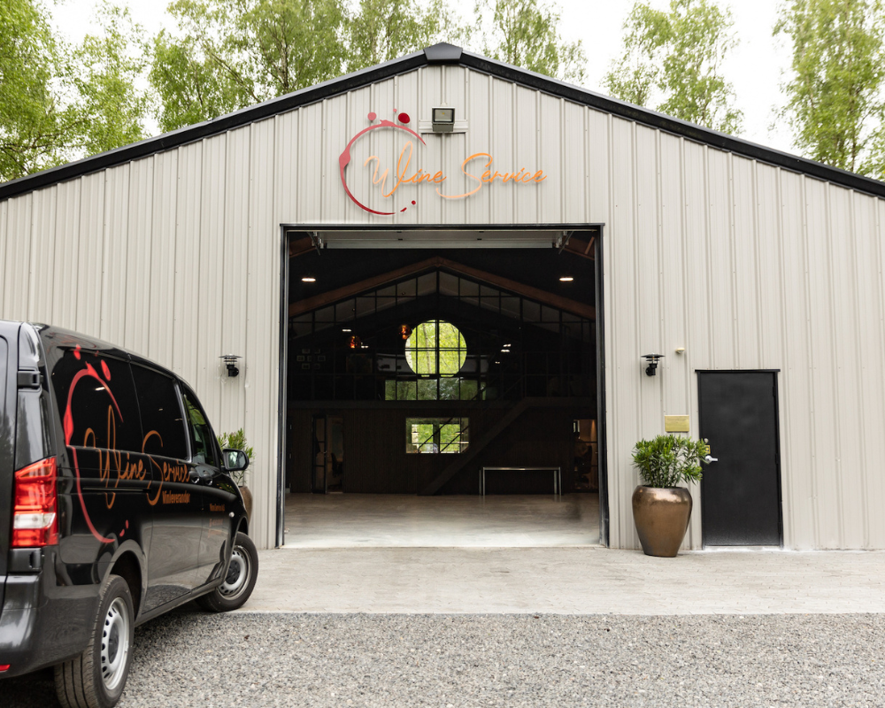 Billede af Mai-Britt med et vinglas, som kigger ud i naturen