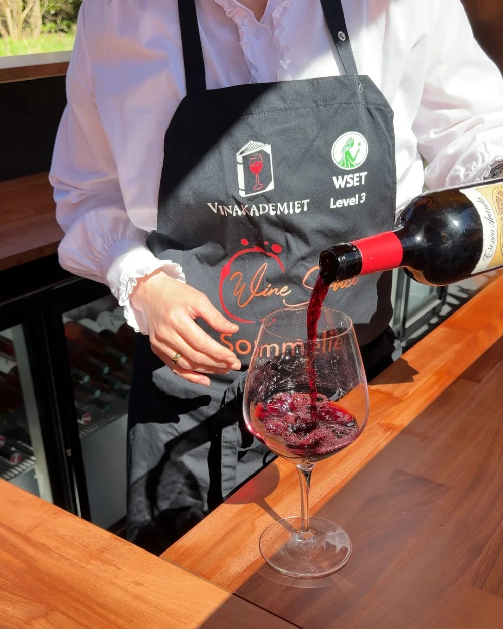 Sommelier hælder rødvin i et vinglas i vinbaren
